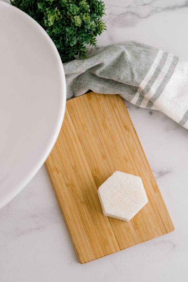 A wooden cutting board with cheese on it.